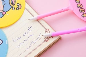 Close-up of pink angel fan pens writing on a notebook with cute cartoon decorations