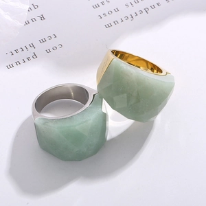 Macro view of wide 18K gold ring with large faceted light green natural stone