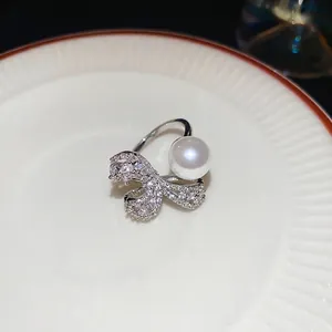 Elegant silver open ring with large white pearl and zircon bow on a ceramic plate