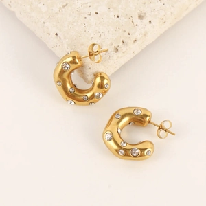 Golden C-shaped hoop earrings with sparkling cubic zirconia on a minimalist stone setting