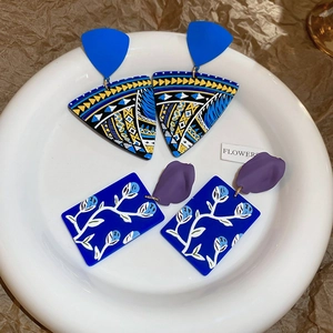 Detail of colorful bohemian painted flower earrings with ethnic patterns on a white plate