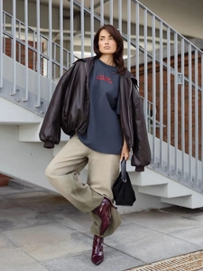 Λεπτομέρεια από oversize βαμβακερό t-shirt με στάμπα κάτω από δερμάτινο σακάκι