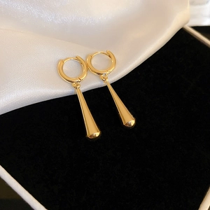 Detailed view of long gold teardrop earrings with mirror finish on white silk and black velvet
