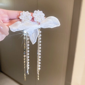 Close-up of white flower earrings with organza bows and pearl chain tassels
