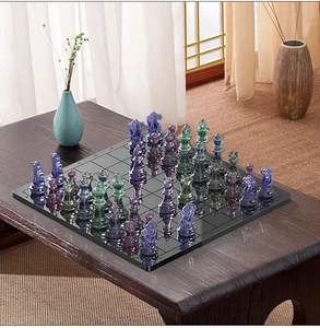Detailed top view of complete crystal resin chess set with colorful pieces on black board