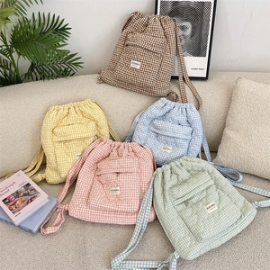 Detailed flat lay of quilted plaid drawstring backpacks in various pastel colors on a sofa