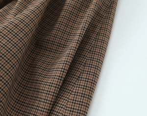 Detail of brown plaid woven fabric showing twill weave and pocket edge stitching