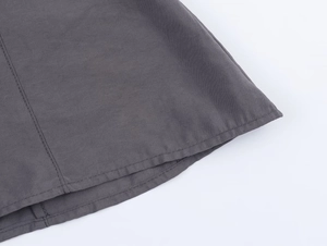 Detailed close-up of dark gray cotton shirt hem showing precise double stitching work