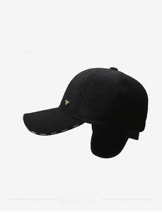Detail of winter baseball cap with ear flaps and Prada-style metal triangle logo