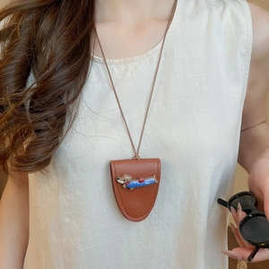 Detail of brown leather neck pouch with a cute dachshund puppy and blue shirt charm