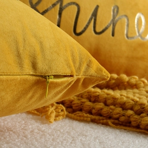 Close-up detail of yellow velvet cushion cover, highlighting hidden zipper and soft texture.