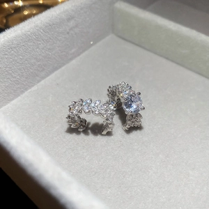 Macro detail of silver zircon leaf clip earrings on a grey velvet jewelry box padding