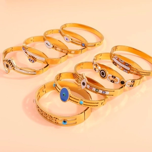 Close-up of gold titanium steel bracelets featuring enamel evil eye designs and rhinestones