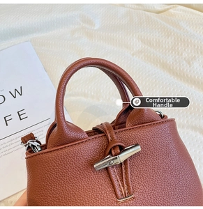 Detailed macro view of brown lychee grain leather texture and metallic bamboo toggle closure