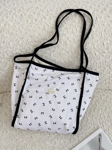 Borsa tote bianca in tela con stampa a fiocchi neri e doppi manici su sfondo soffice
