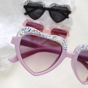 Macro shot of heart-shaped sunglasses with glitter frame in pink and black colors