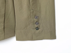 Détail de la manche d'un blazer vert olive avec trois boutons perlés et coutures nettes