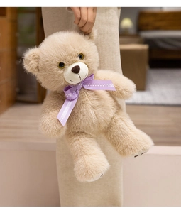 Close-up of fluffy plush teddy bear with a purple polka dot bow in a cozy home setting