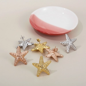 Starfish earrings in gold, silver, and rose gold finishes on a minimalist background
