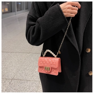 Detail of pink jelly bag with quilted texture, pearl handle and gold chain strap