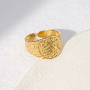 Detailed close-up of golden Saint Benedict medal ring with Jesus engraving and matte texture