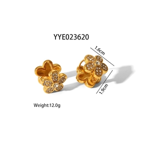 Détail de boucles d'oreilles fleurs en or avec pavé de zircones et pierre centrale