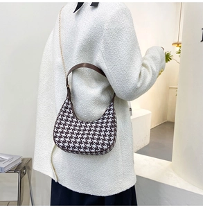 Detail of houndstooth crescent bag with brown leather strap and gold chain accent