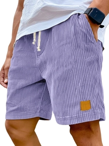 Close-up of purple corduroy shorts featuring elastic drawstring waist and brown leather patch