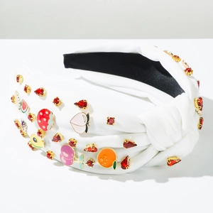 Close-up of knotted white headband featuring 3D fruit charms and red rhinestones