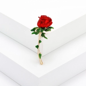 Vintage red rose brooch with green leaves and gold stem on white background