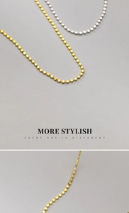 Macro shot of minimalist silver and gold beaded ball chain necklaces with smooth finish