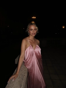 Elegant pink satin slip dress with V-neckline modeled in a sophisticated night scene