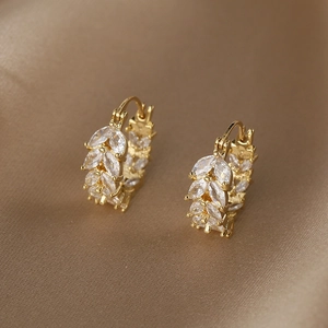 Gros plan de boucles d'oreilles feuilles dorées avec cristaux sur soie marron