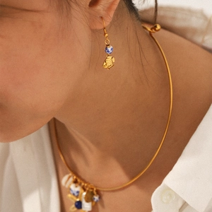 Detailed view of gold tropical fish earrings and necklace set with blue ceramic beads