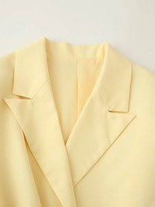 Détail d'un blazer jaune clair montrant le col à revers et la texture du sergé