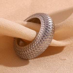 Macro view of silver C-shaped earring featuring detailed fish scale texture on satin