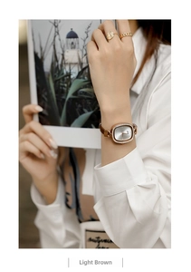 Close-up of a small oval vintage quartz watch with rhinestone bezel on a brown leather strap