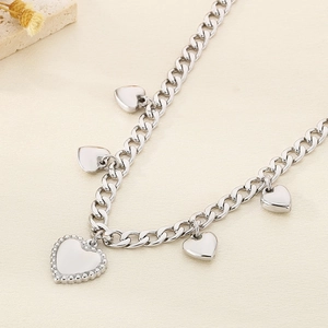 Macro detail of silver stainless steel flat link necklace with five heart charms and beads