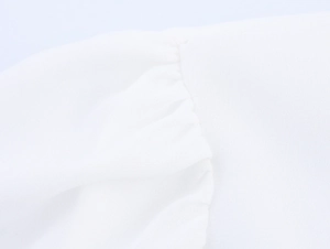 Detailaufnahme einer weißen eleganten Plissee-Bluse mit Fokus auf Stoffstruktur und Naht