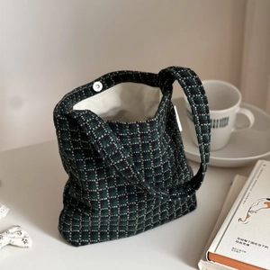 Detail of dark green checkered knit tote bag showing the magnetic buckle and woven texture