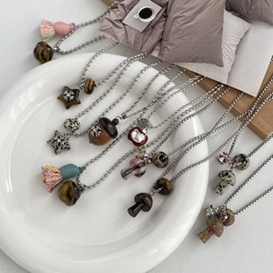 Detailed flat lay of diverse mushroom and acorn pendants on silver ball chains