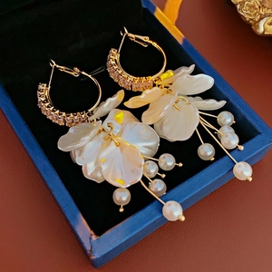 Elegant zircon flower pearl tassel earrings in gold set on a blue velvet jewelry box