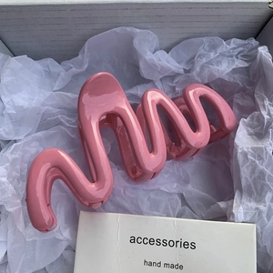 Macro shot of large glossy pink wave hair claw clip inside a white gift box
