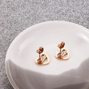 Close-up of rose gold hollow heart stud earrings featuring mum letters on ceramic tray