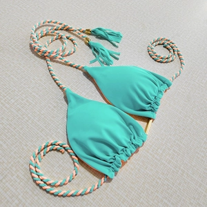 Detail of mint green bikini top with orange lining, braided ties and tassel charms