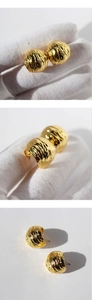 Macro detail of gold plated C-shaped earrings showing pleated texture and metallic finish