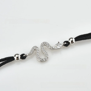 Macro shot of silver snake charm with white zircons and adjustable black woven cord