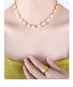 Close-up of French-style baroque pearl necklace and gold ring worn with yellow knitwear