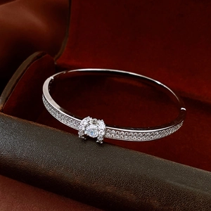 Macro shot of a silver-tone pavé bangle featuring a central gemstone in a luxury gift box