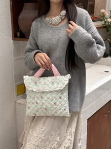 Detail of light green quilted laptop bag with cute rabbit pattern and lace trim